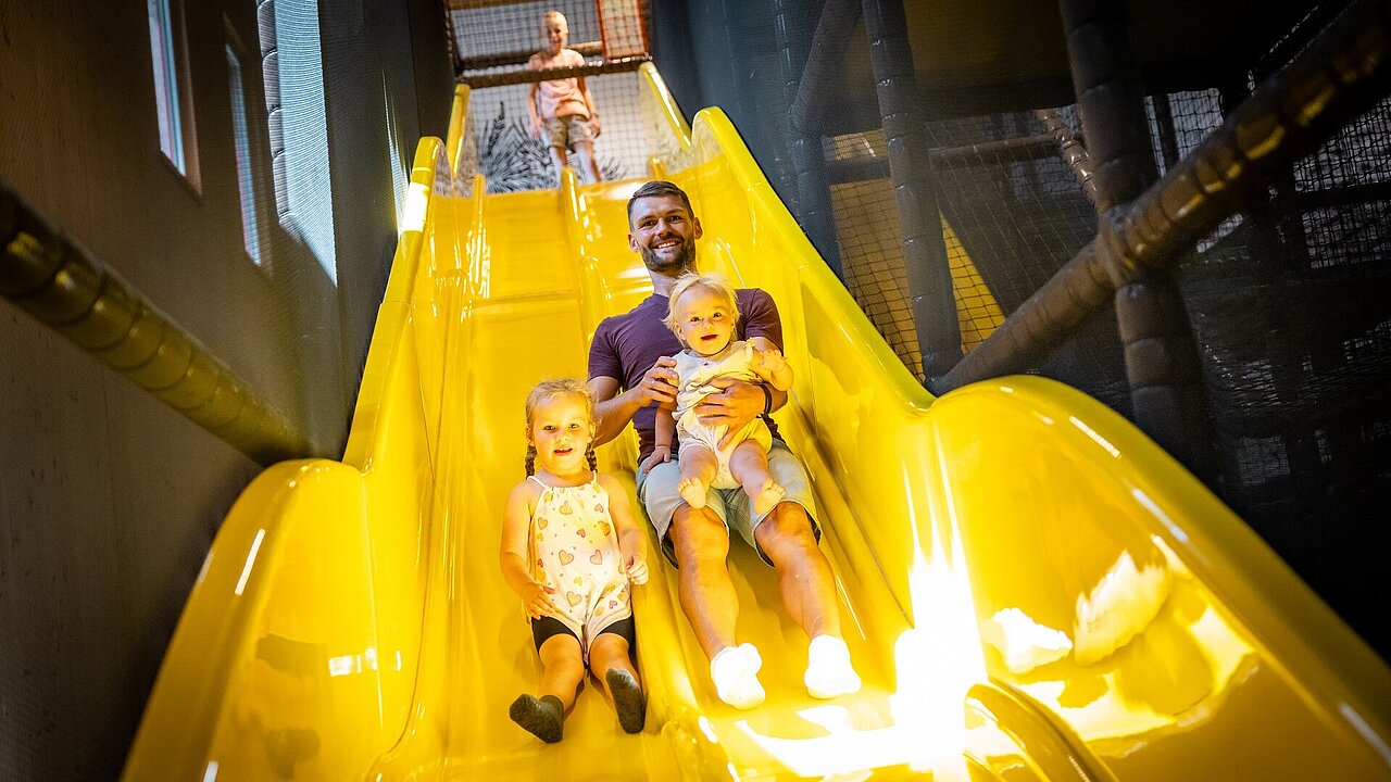 Papa rutscht mit Kindern im Elldus Resort die Rutsche herunter 