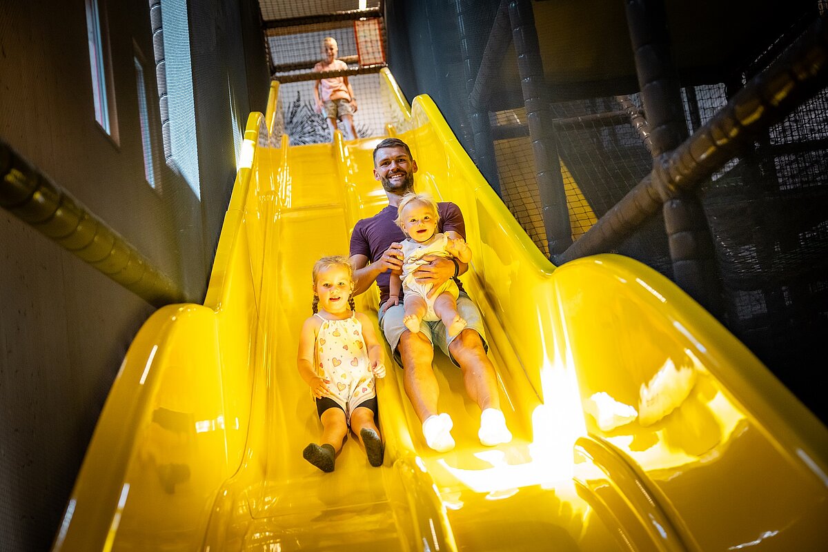 Papa rutscht mit Kindern im Elldus Resort die Rutsche herunter 